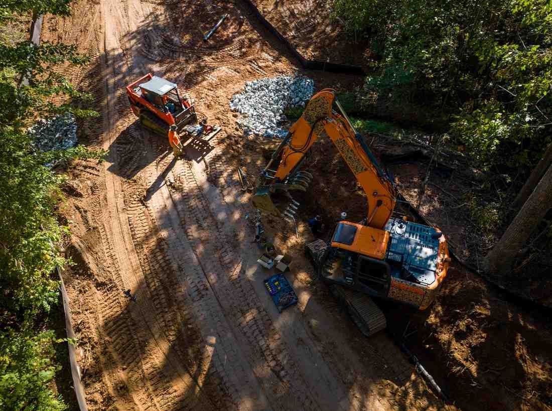 Aerial view of construction site with an excavator and a skid steer next to piles of gravel and dirt.